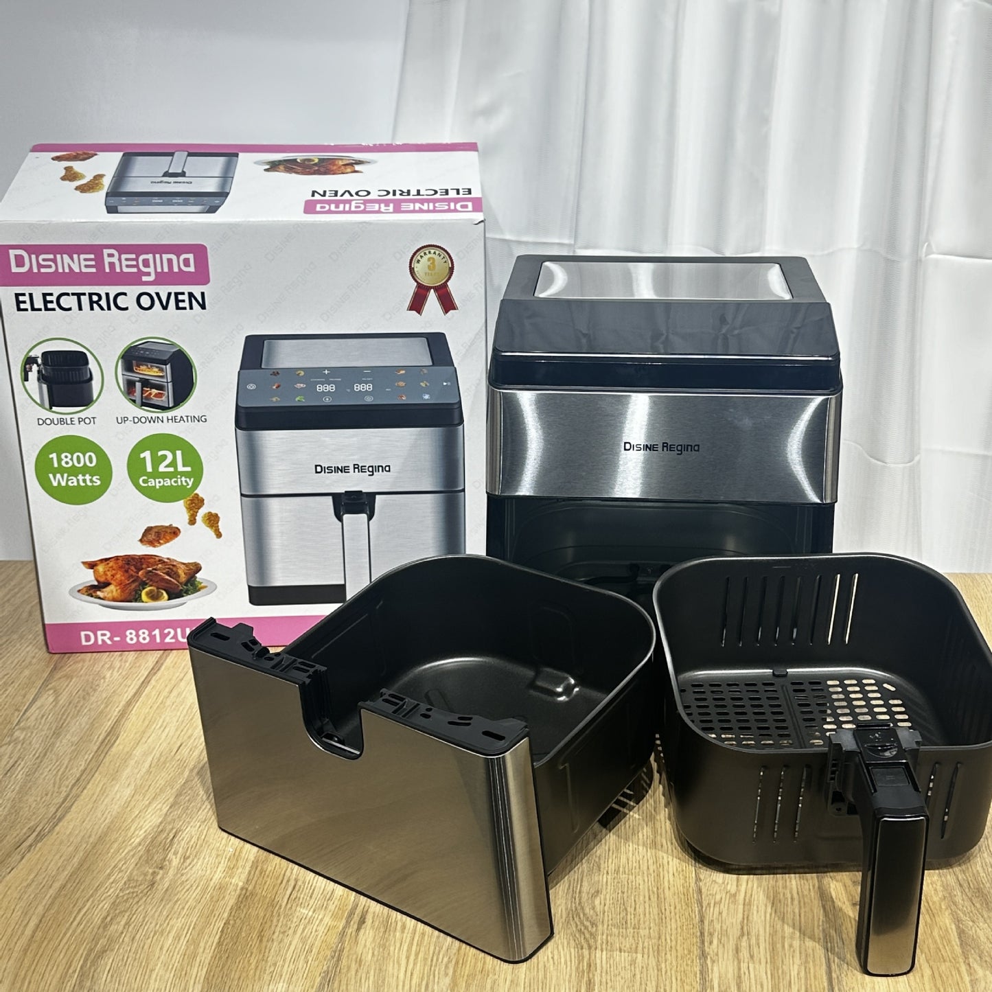 Electric oven with detachable parts on a wooden surface, accompanied by its packaging.