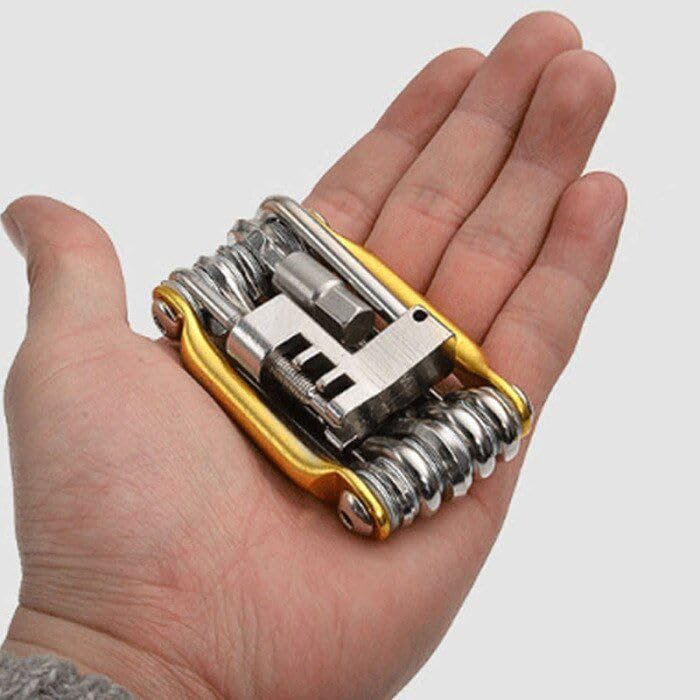 Multitool with various attachments held in a hand against a white background