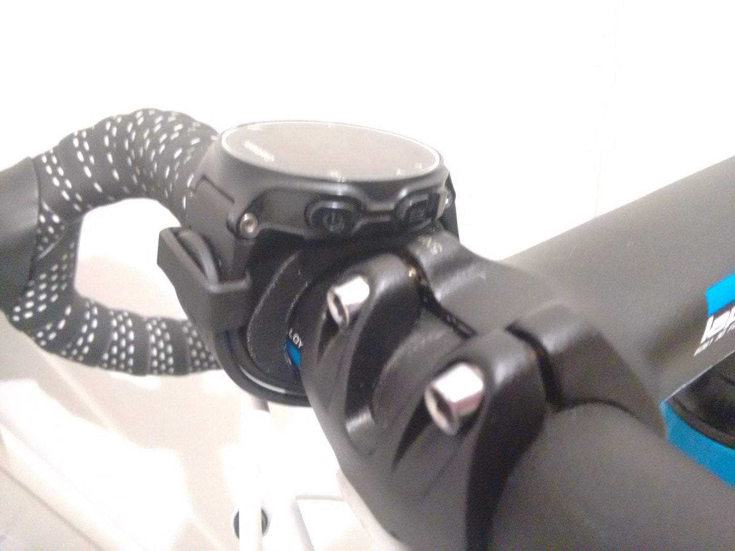Close-up of a bike handlebar with a black and white glove on the left and a black bike bell on the right.