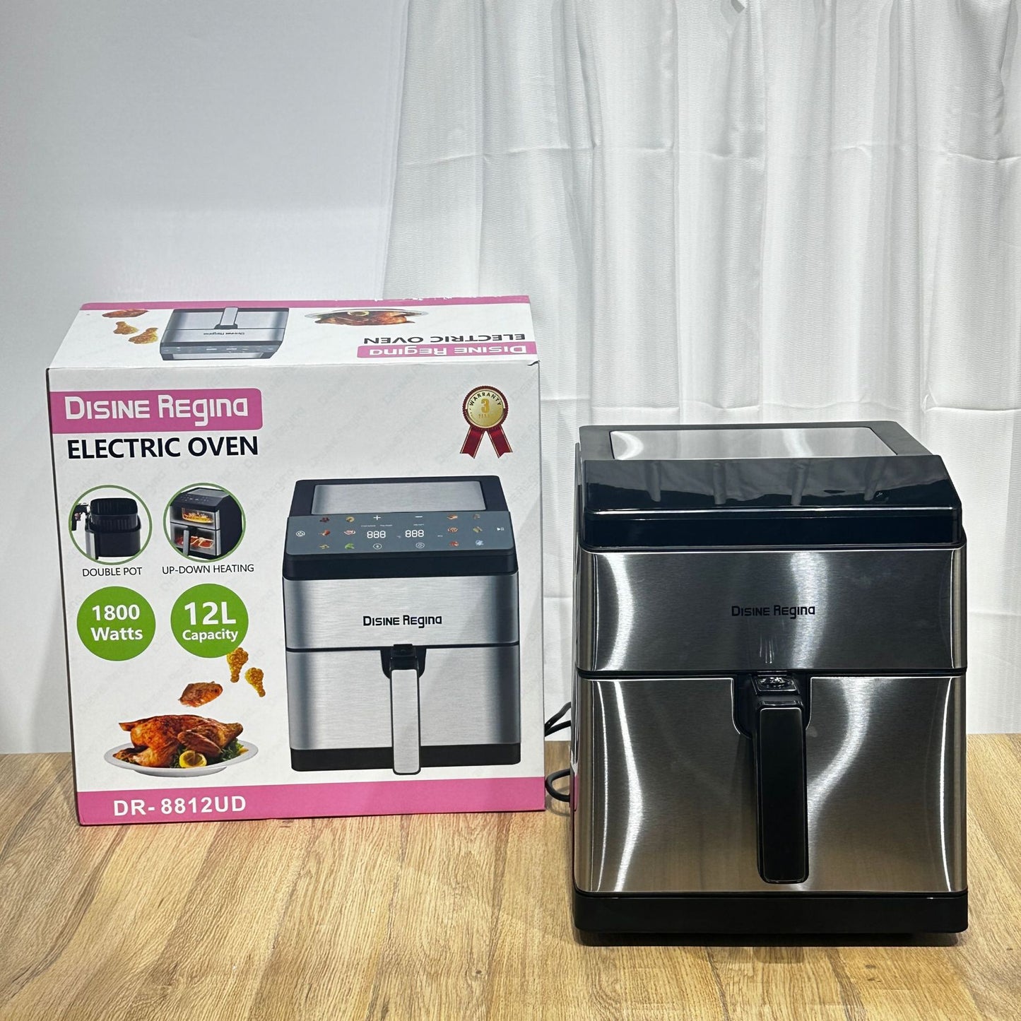 Stainless steel electric oven with packaging on a wooden surface