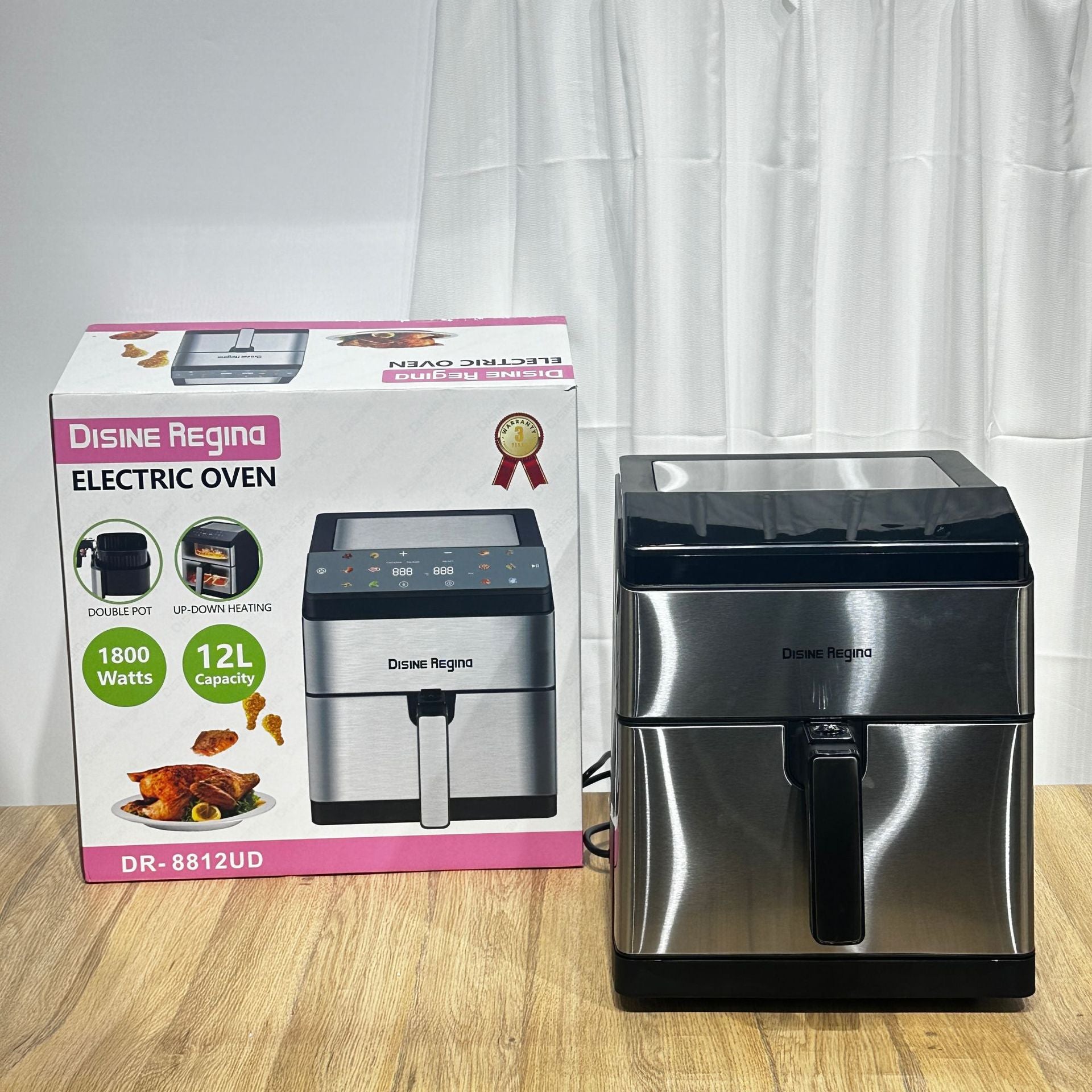 Stainless steel electric oven with packaging on a wooden surface